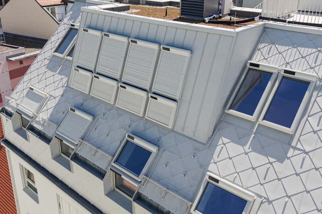 Dachfläche mit solarbetriebenen Außenrollläden und Dachflächenfenstern an einem Wohnhaus in Wien